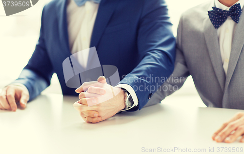 Image of close up of happy male gay couple holding hands