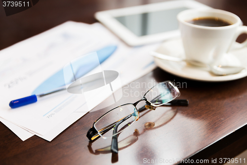 Image of close up of glasses, tablet pc, charts and coffee