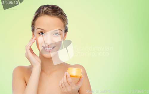 Image of happy young woman applying cream to her face