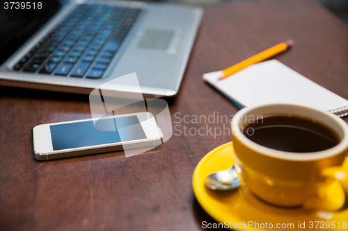 Image of close up of smartphone, coffee cup and laptop