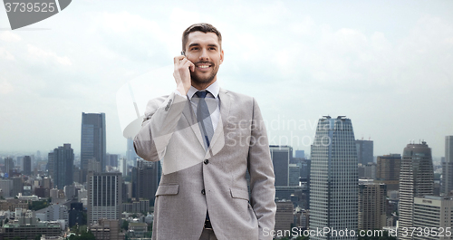 Image of smiling businessman with smartphone in city