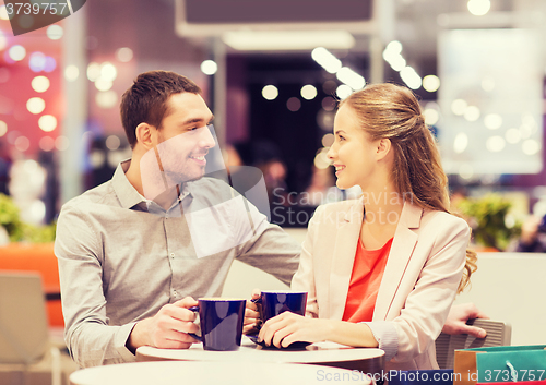 Image of happy couple with shopping bags drinking coffee