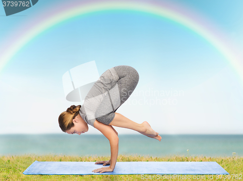 Image of woman making yoga in crane pose on mat