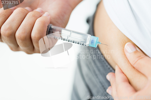 Image of close up of hands making injection by insulin pen