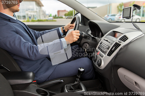 Image of close up of young man in suit driving car