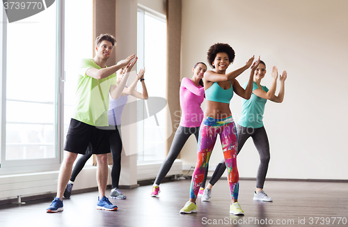 Image of group of smiling people dancing in gym or studio