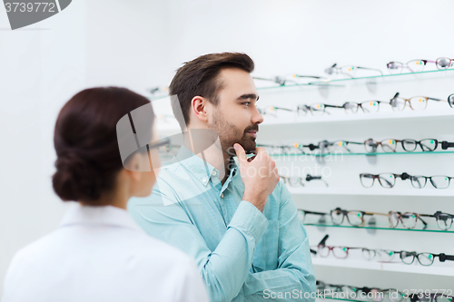 Image of optician showing glasses to man at optics store