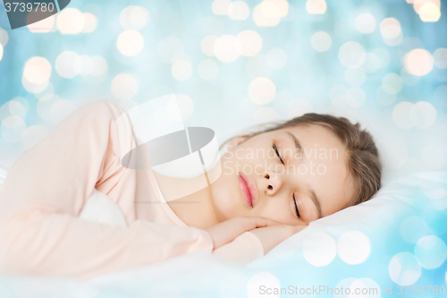 Image of girl sleeping in bed over blue lights background