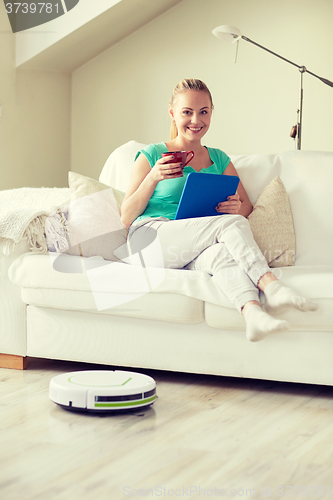 Image of happy woman with tablet pc drinking tea at home