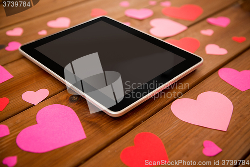 Image of close up of tablet pc and hearts on wood