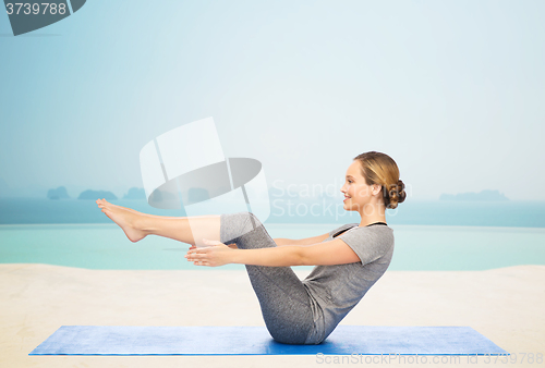 Image of woman making yoga in half-boat pose on mat