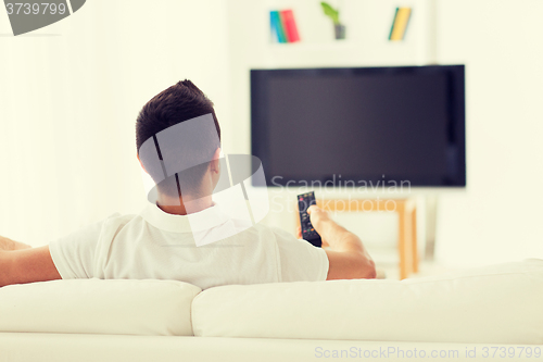 Image of man watching tv and changing channels at home