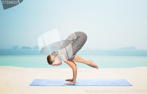 Image of woman making yoga in crane pose on mat
