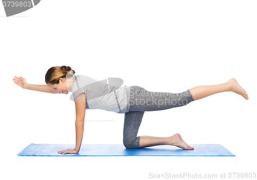 Image of woman making yoga in balancing table pose on mat