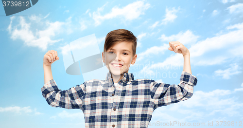 Image of happy boy in checkered shirt showing strong fists