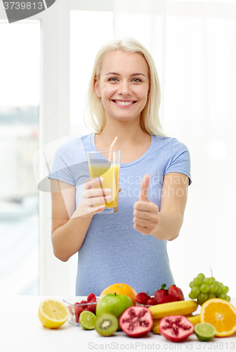 Image of woman drinking fruit juice and showing thumbs up