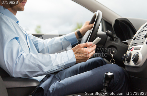 Image of close up of man with smartphone driving car