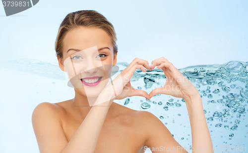 Image of smiling young woman showing heart shape hand sign