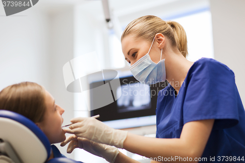 Image of female dentist checking patient girl teeth