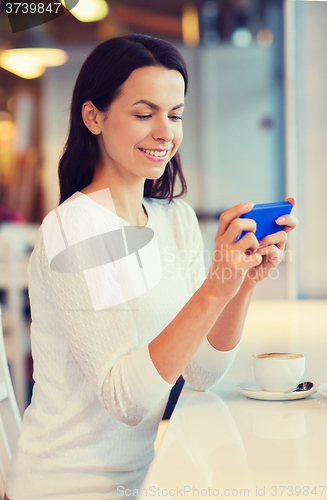 Image of smiling woman with smartphone and coffee at cafe