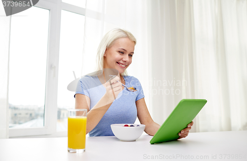 Image of woman with tablet pc eating breakfast at home