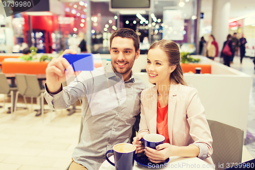 Image of happy couple with smartphone taking selfie in mall