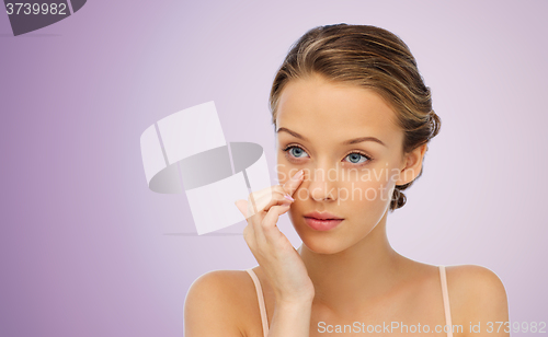 Image of young woman applying cream to her face