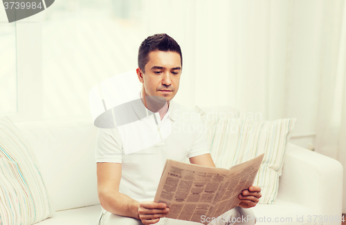 Image of man reading newspaper at home