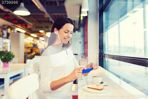 Image of smiling woman with smartphone and coffee at cafe