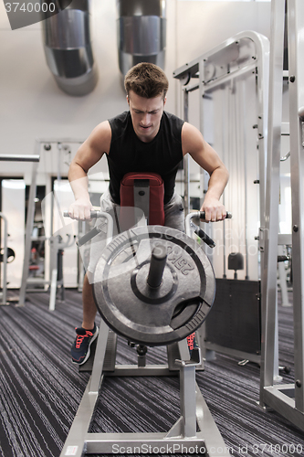 Image of young man exercising on t-bar row machine in gym