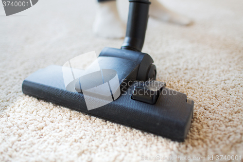 Image of close up of vacuum cleaner cleaning carpet at home