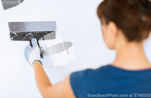 Image of woman plastering the wall with trowel