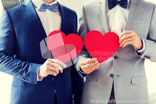 Image of close up of male gay couple holding red hearts