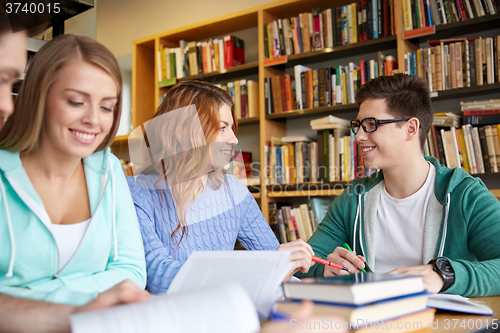 Image of happy students writing to notebooks in library