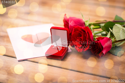 Image of close up of diamond ring, roses and greeting card