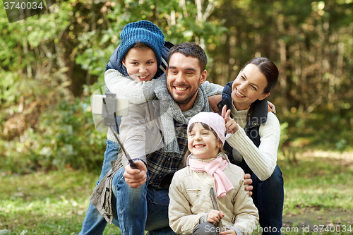 Image of happy family with smartphone selfie stick in woods