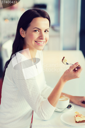 Image of smiling young woman with cake and coffee at cafe