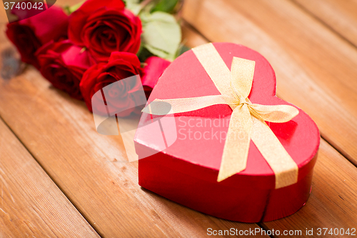 Image of close up of heart shaped gift box and red roses