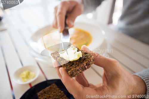 Image of close up of hands applying butter to bread