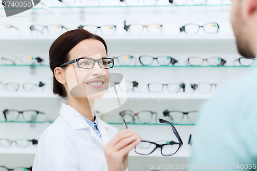 Image of optician showing glasses to man at optics store