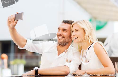Image of happy couple taking selfie with smartphone at cafe