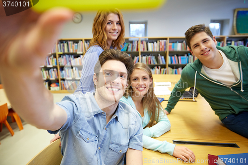 Image of students with smartphone taking selfie in library