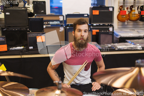 Image of male musician with cymbals at music store