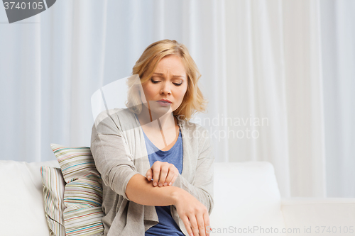 Image of unhappy woman suffering from hand inch at home