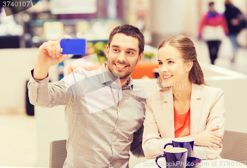 Image of happy couple with smartphone taking selfie in mall