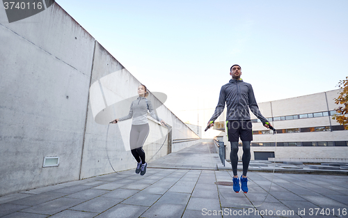 Image of man and woman exercising with jump-rope outdoors