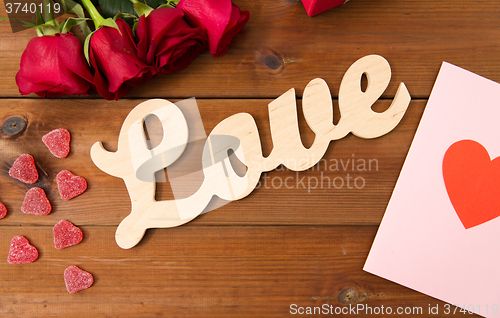 Image of close up of gift box, red roses and greeting card