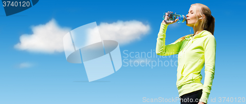 Image of woman drinking water after doing sports outdoors