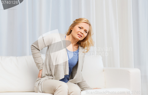 Image of unhappy woman suffering from backache at home