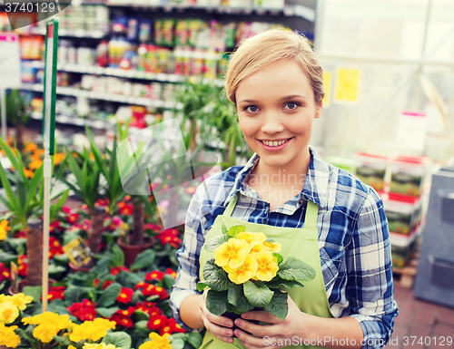 Image of happy woman holding flowers in greenhouse